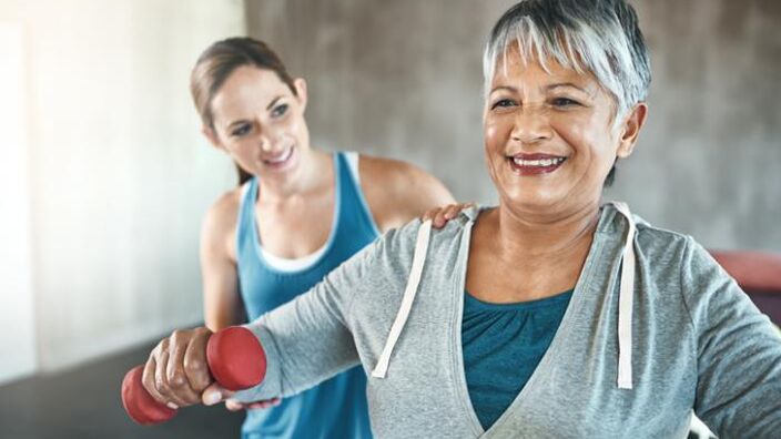 An Older Woman Exercising With An Instructor